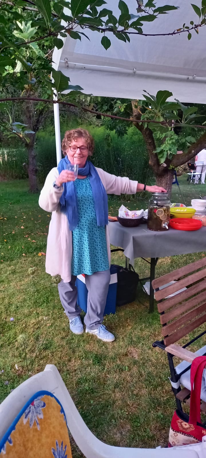 Simone steht mit einem Glas in der Hand im Garten