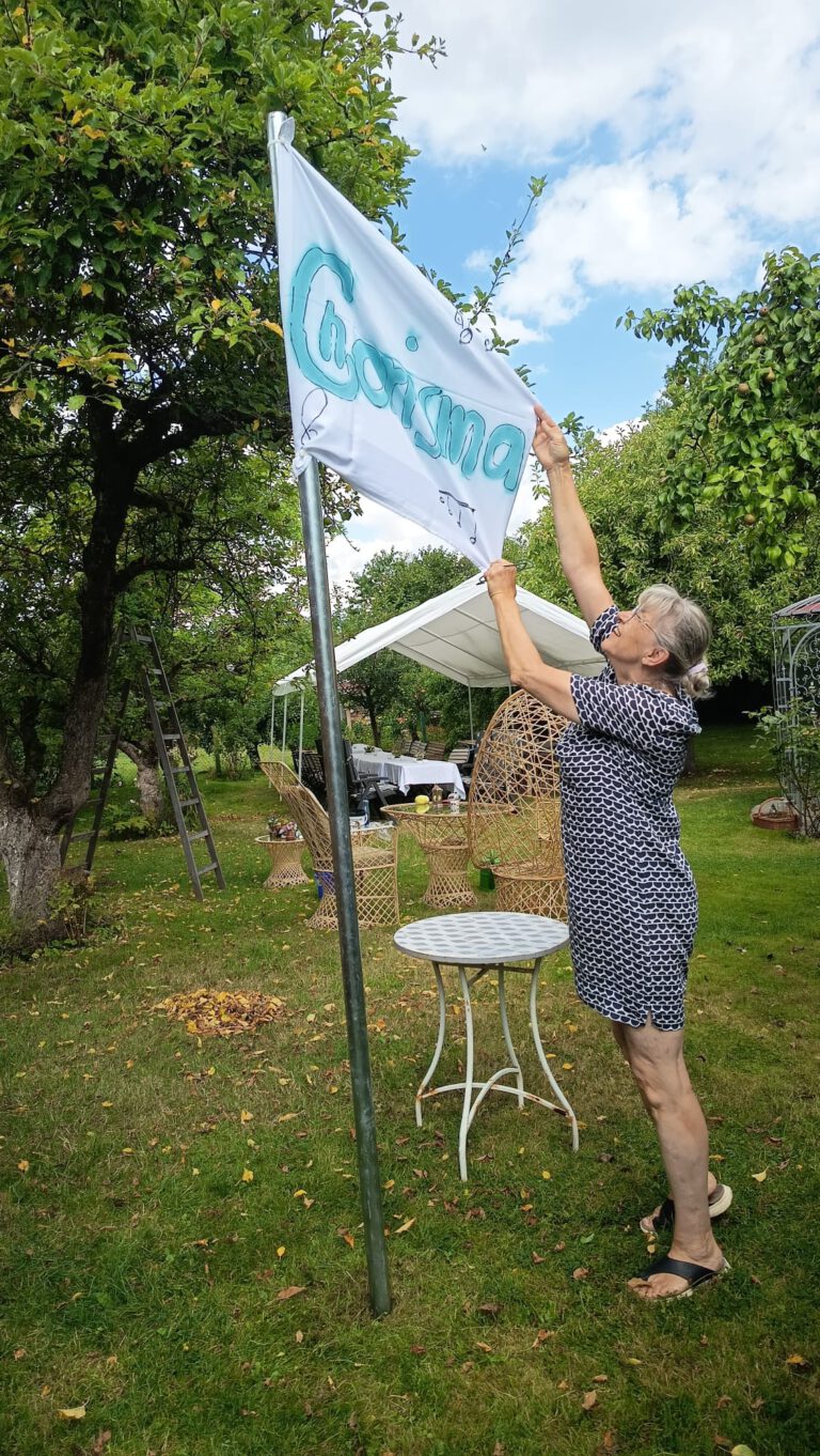 Eine Sängerin zieht die Chorisma-Fahne im Garten am Mast hoch
