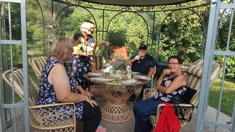 Gäste sitzen an einem runden Tisch im Gartenpavillon