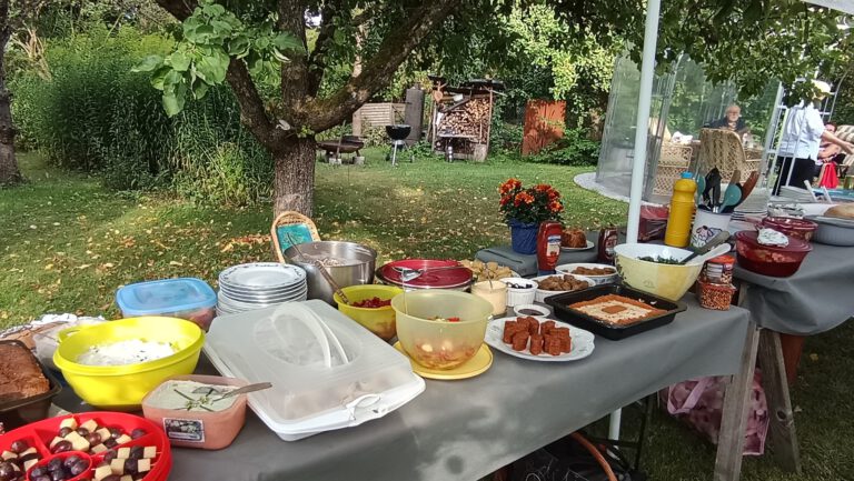 Schüsseln, Teller und Kuchen auf der Büfetttafel unter den Obstbäumen