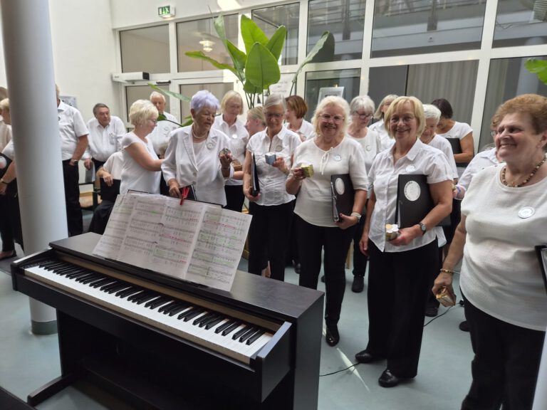 Der Chor singt im Paul-Gerhardt-Haus, im Vordergrund ein Klavier mit aufgeschlagenen Noten