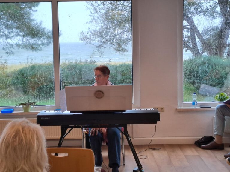 Chorleiterin Christiane Fuhrmann am E-Piano vor dem Fenster zum Meer