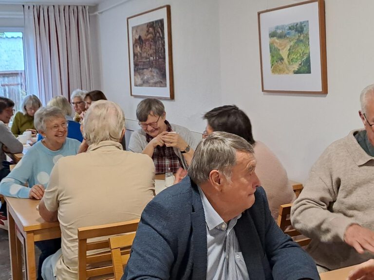 Chormitglieder sitzen bei Kaffee und Kuchen an langen Tischen